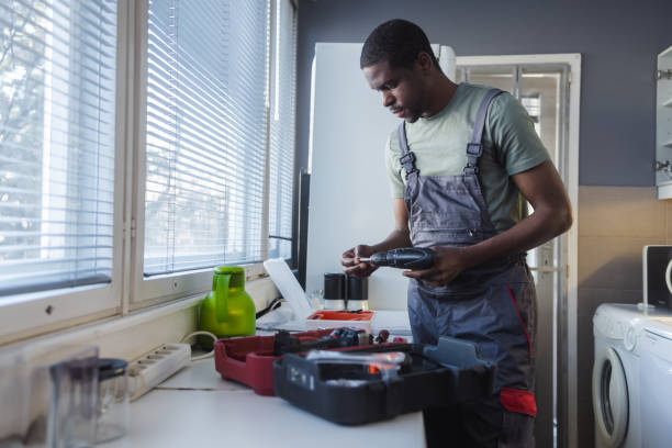 Photo of African American handyman working in the customer's kitchen